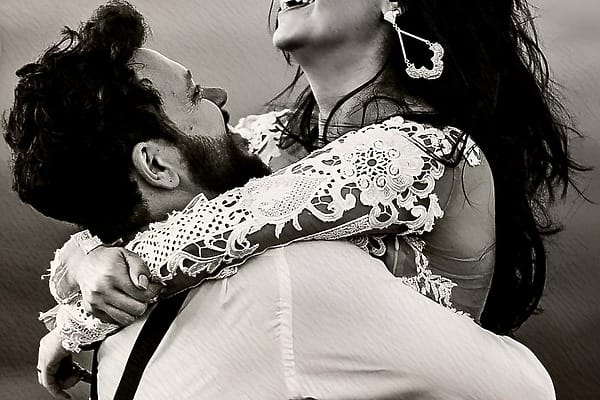 A couple in wedding attire embracing and laughing at their SLS Playa Mujeres destination wedding.
